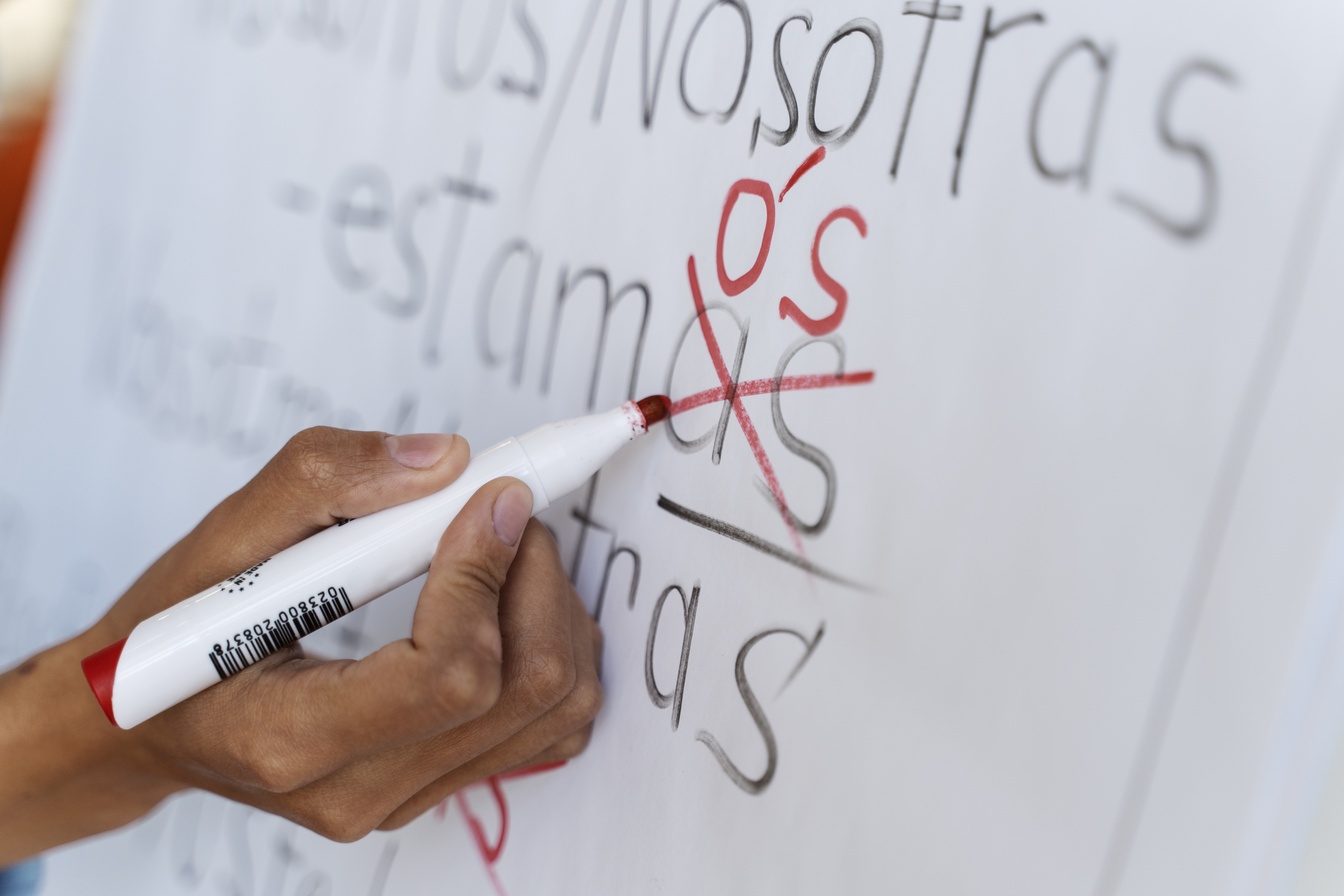 Una mano escribiendo en una pizarra blanca