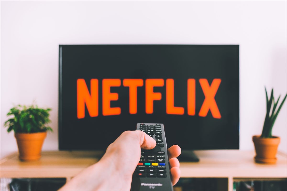 A TV remote pointing at a screen showing Netflix