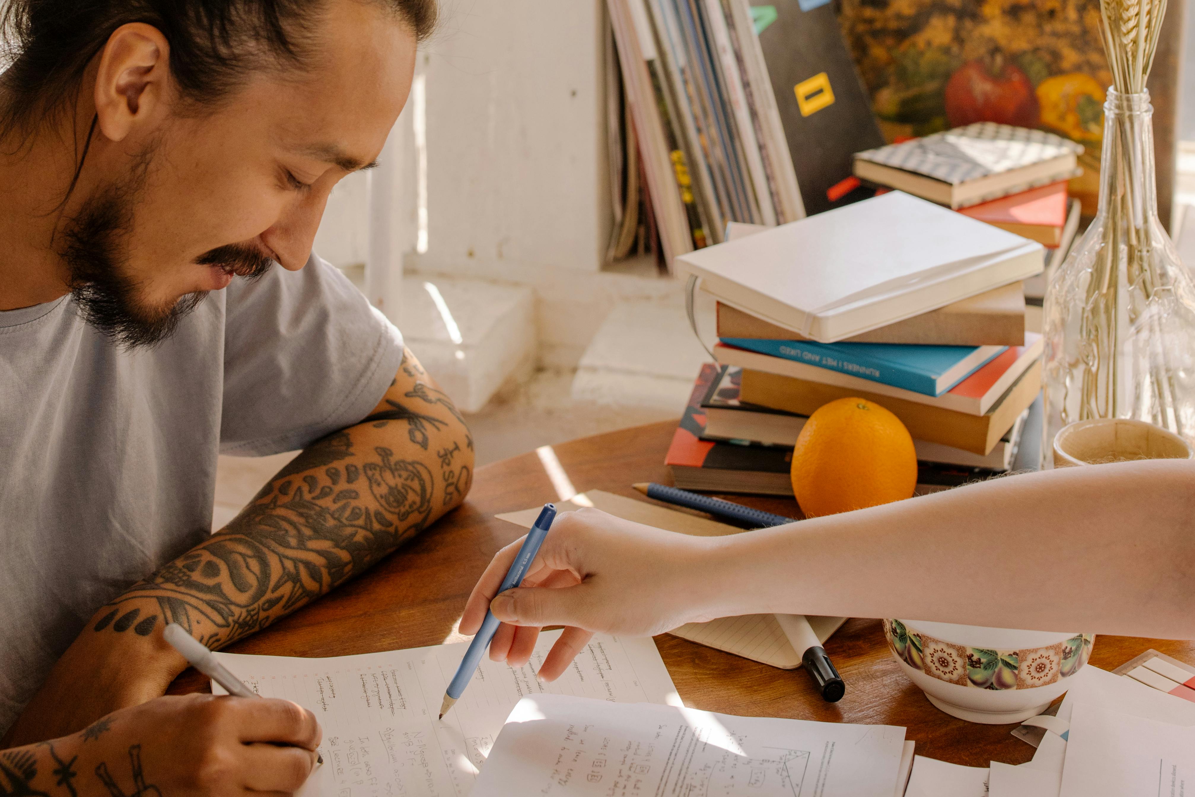 Dos personas estudiando espa&ntilde;ol con libros y cuadernos
